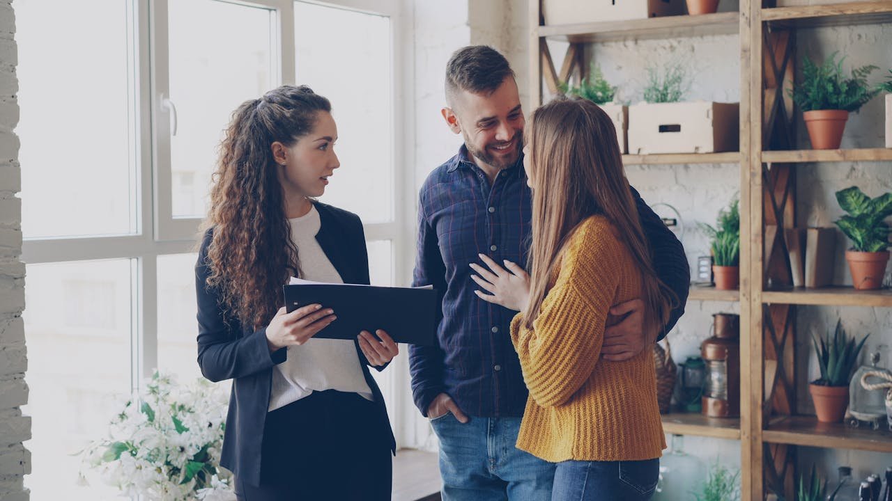 A couple consulting with a real estate agent in a cozy office setting with indoor plants.