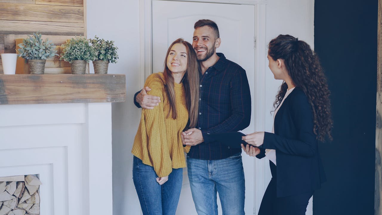 Happy couple meeting with a realtor indoors, discussing property purchase in modern living room.