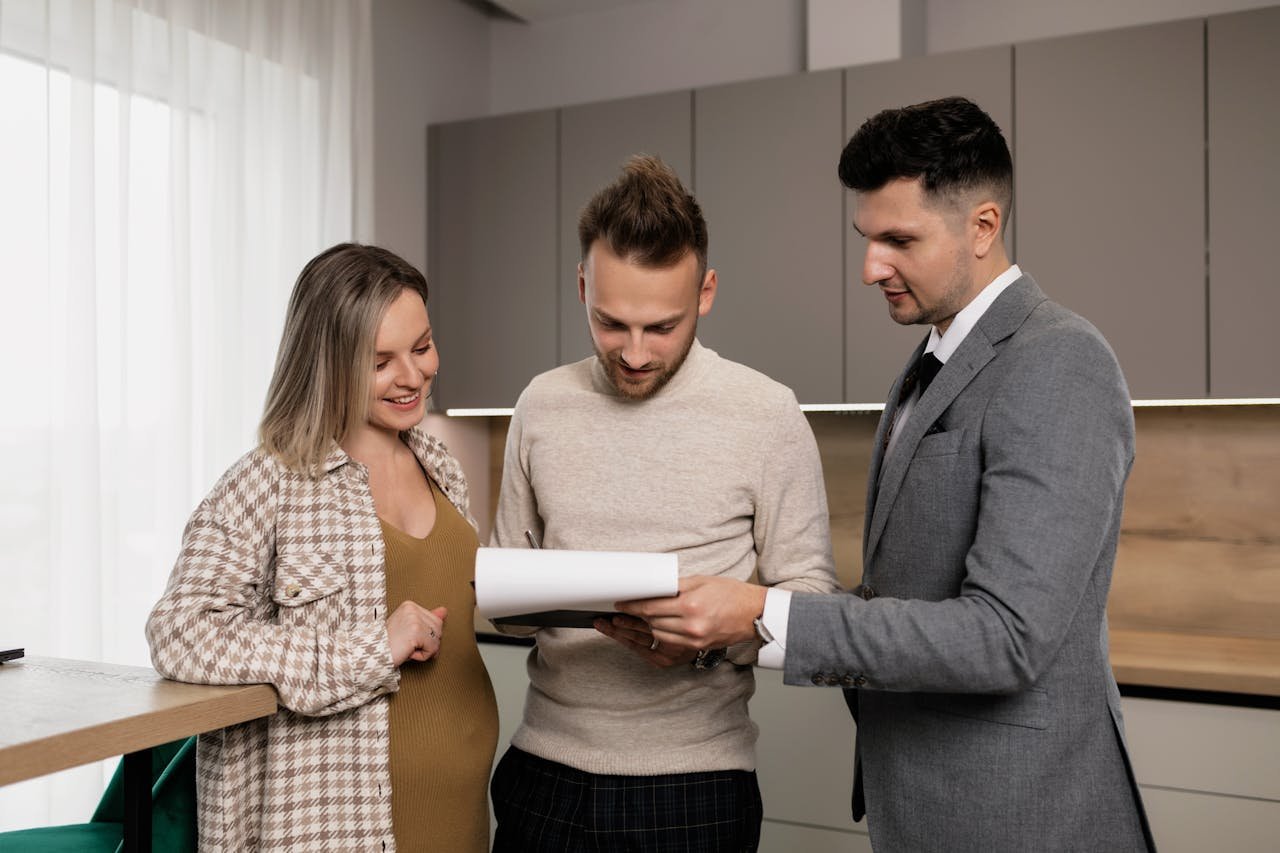 A realtor presents a property contract to a young couple in a modern indoor setting, discussing details.